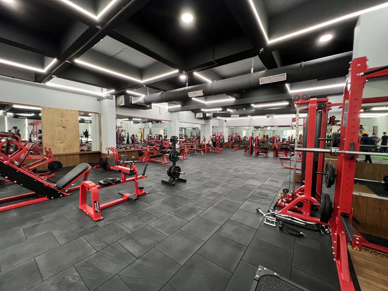 Inside Hustlers Health & Fitness — premium gym floor with red equipment